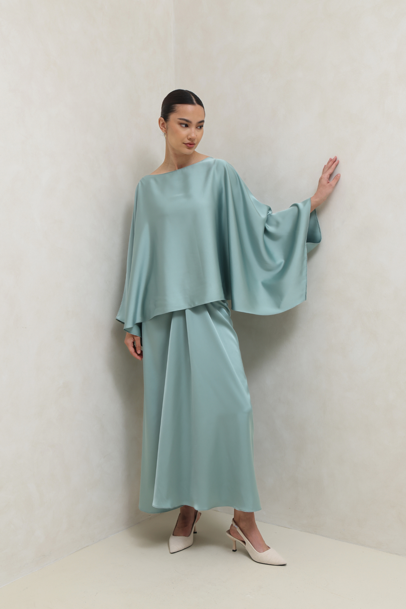 فستان أخضر بتصميم ملتف وأكمام كيب انسيابية