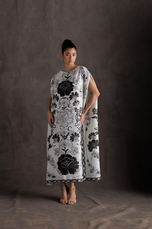 Woman wearing a black and white floral dress against a dark background