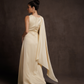 Woman wearing a long, light-colored dress with a cape against a dark background