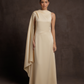 Woman wearing a beige evening gown with a draped effect on a dark background