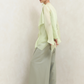 Person wearing a light green outfit with wide-leg pants against a white background