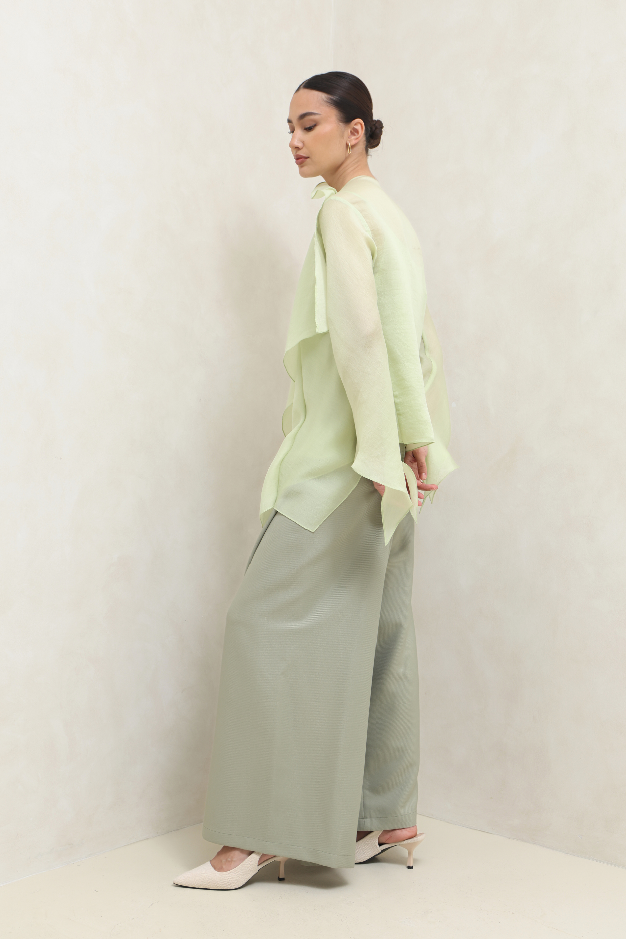 Person wearing a light green outfit with wide-leg pants against a white background