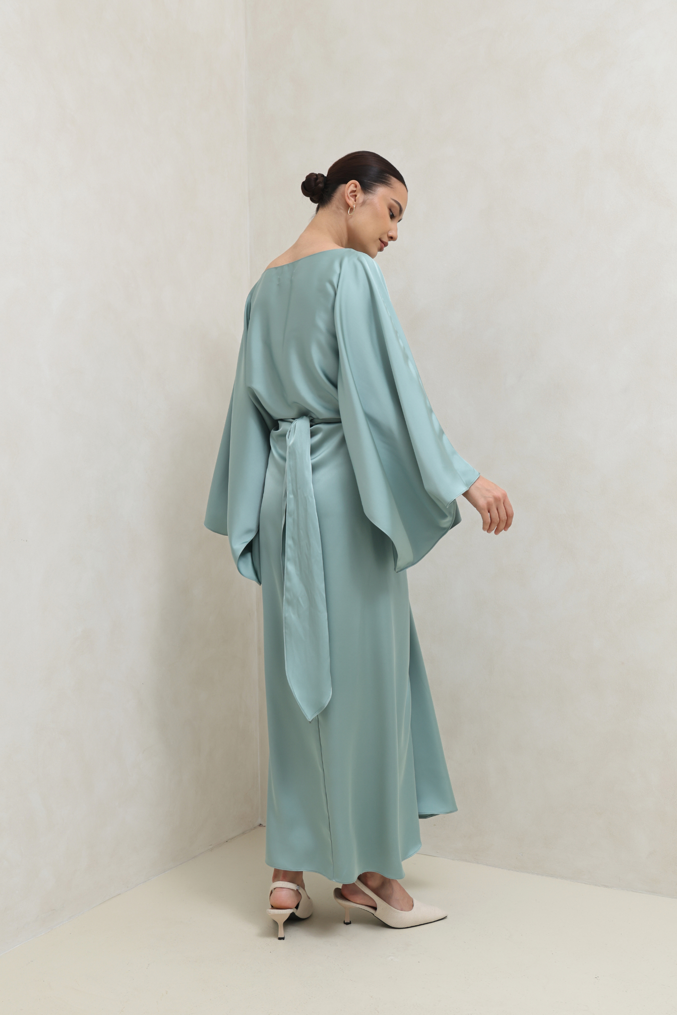 فستان أخضر بتصميم ملتف وأكمام كيب انسيابية