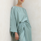 Woman wearing a light blue satin dress against a plain background