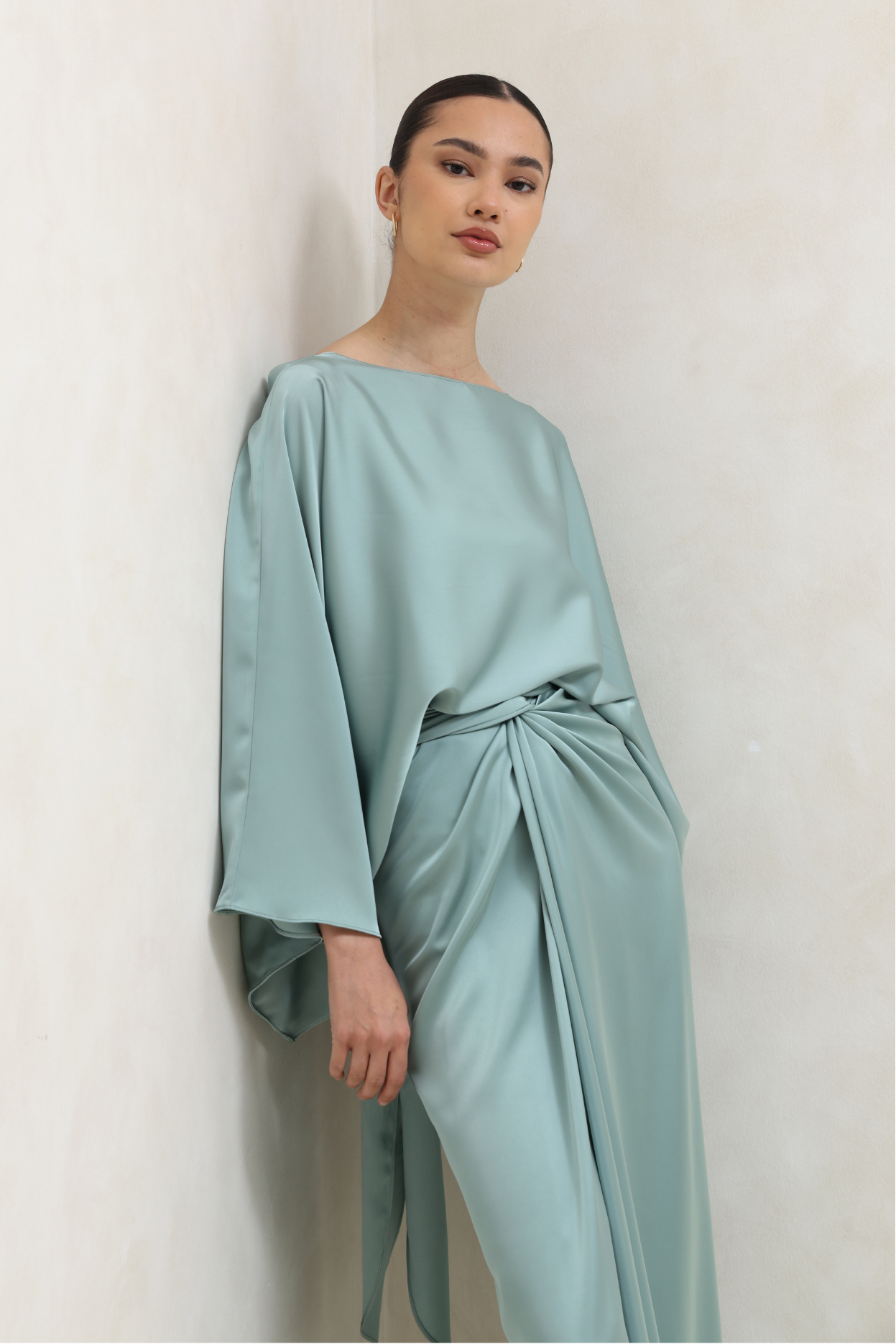 Woman wearing a light blue satin dress against a plain background